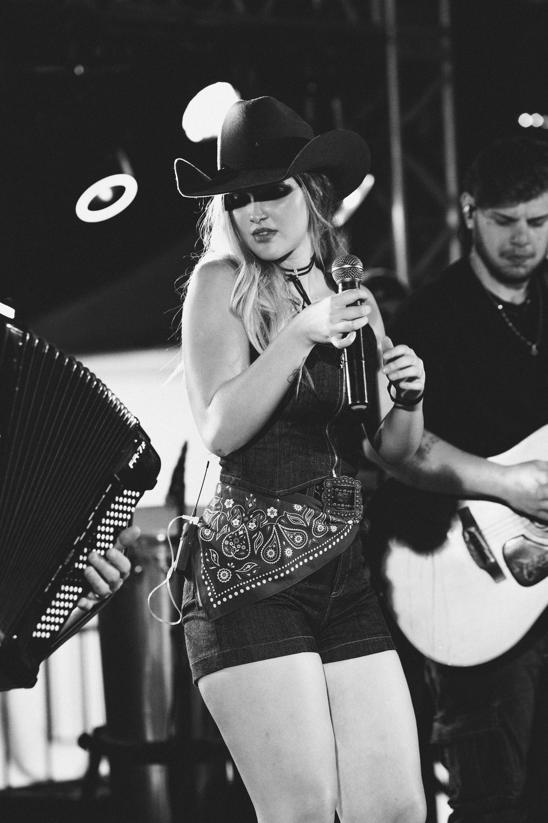 Mari Clemente cantando ao microfone com sanfoneiro e violonista no palco